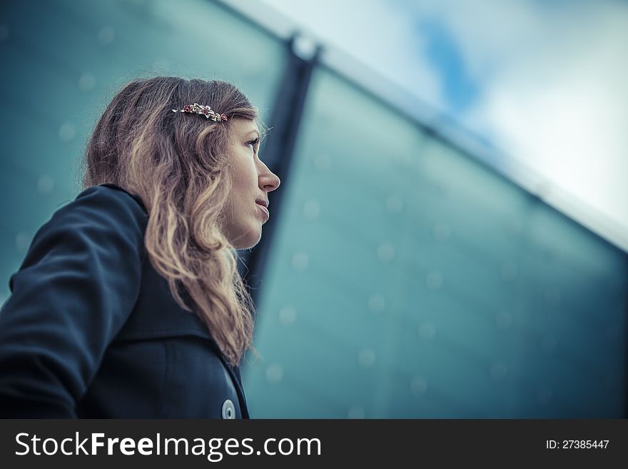 Girl looks on the sky with glass wall on background