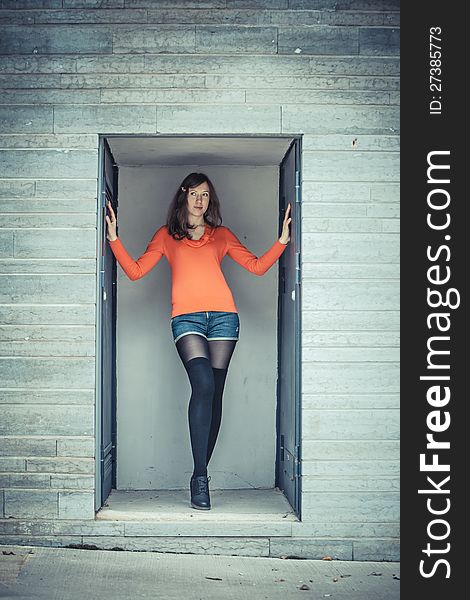 Girl posing in the concrete alcove placing the hands on the wall. Girl posing in the concrete alcove placing the hands on the wall