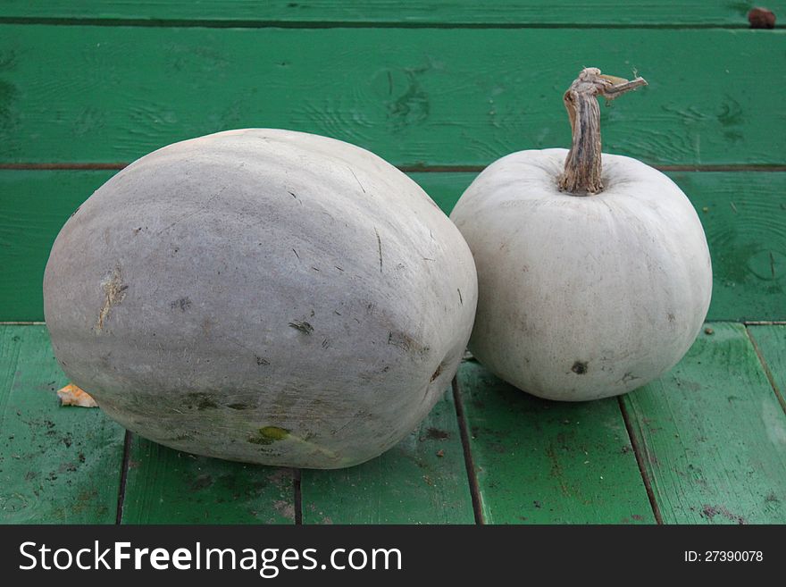 Two pumpkins on the green wooden table