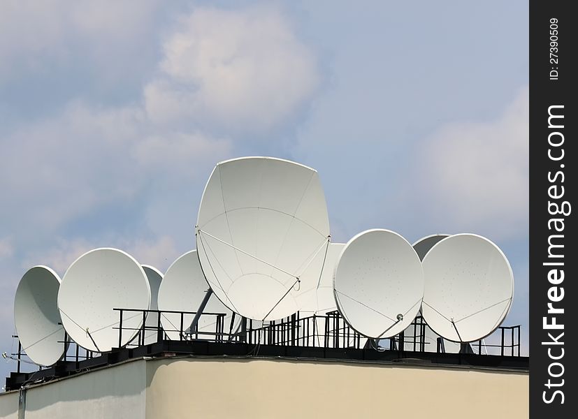 Many satellite dishes on the roof of a building