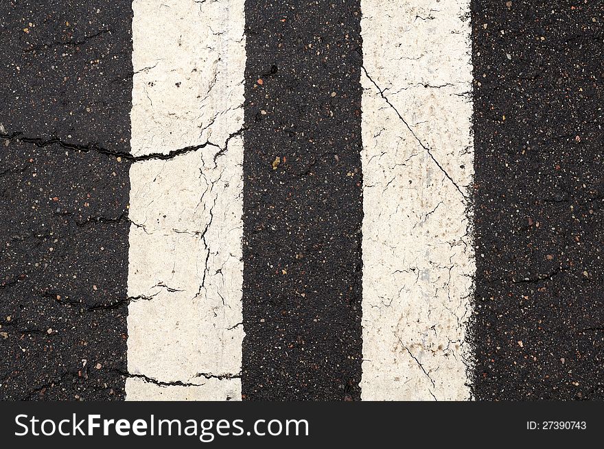 A close-up of white double-line markings on the road. A close-up of white double-line markings on the road