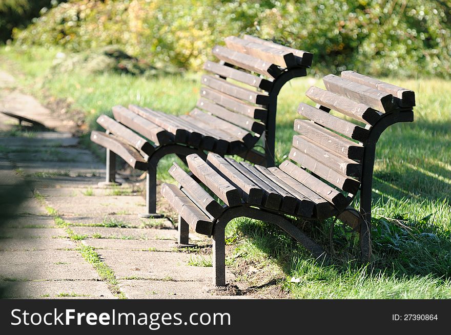 Two empty wooden benches along an old tiled path in the park. Two empty wooden benches along an old tiled path in the park