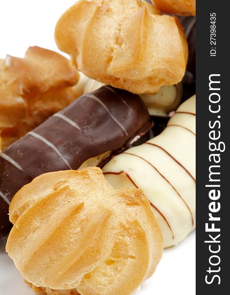Arrangement of Eclair with Dark and White Chocolate Glaze and Profiterole closeup on white background. Arrangement of Eclair with Dark and White Chocolate Glaze and Profiterole closeup on white background