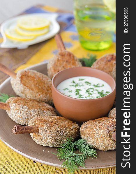Chicken cutlets on a stick of cinnamon with yogurt sauce