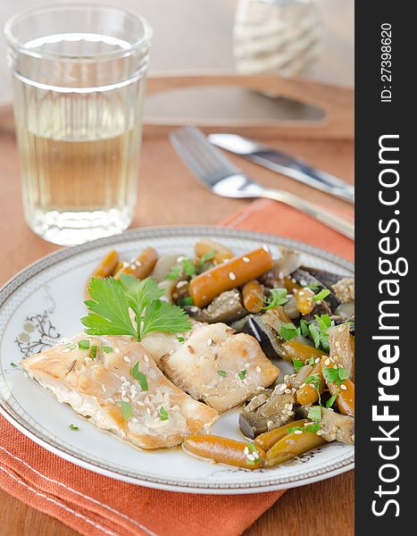 Sliced â€‹â€‹baked cod with vegetables on the plate on the decorated table. Sliced â€‹â€‹baked cod with vegetables on the plate on the decorated table