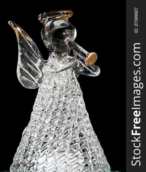 Ange-Statuette consisting of glass, playing a trumpet in front of black background. Ange-Statuette consisting of glass, playing a trumpet in front of black background