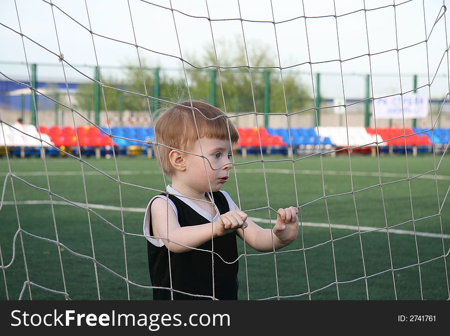 The boy in a grid of a football gate before the beginning of game. The boy in a grid of a football gate before the beginning of game