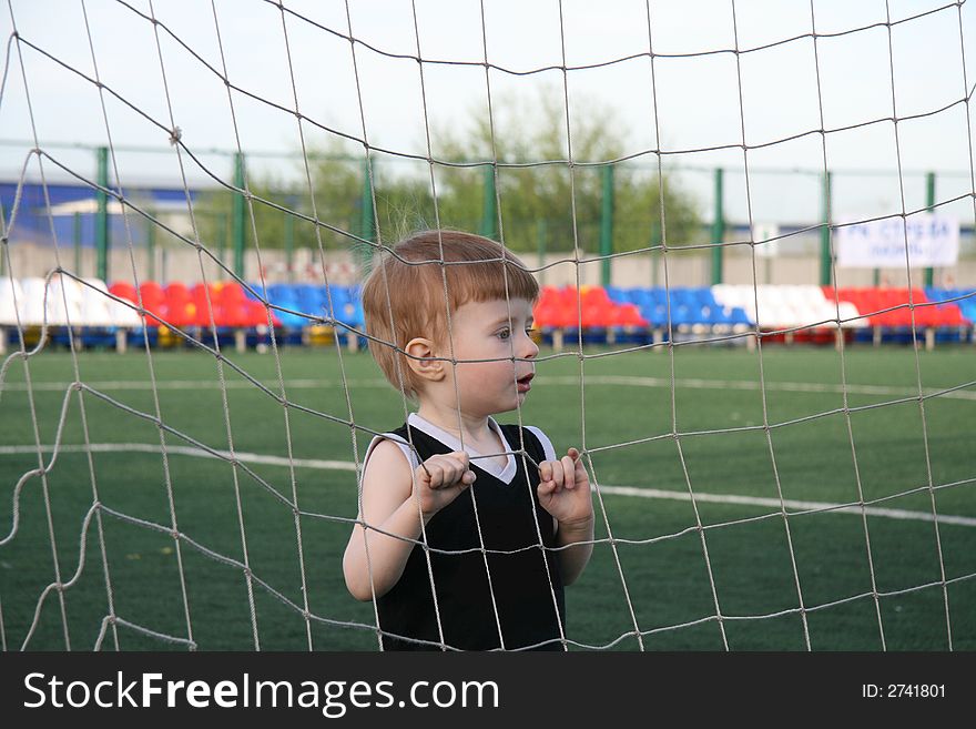 The boy in a grid of a football gate before the beginning of game. The boy in a grid of a football gate before the beginning of game