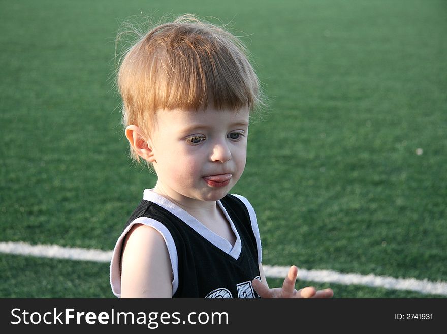 The fair-haired boy in the empty stadium, covered by the evening sun