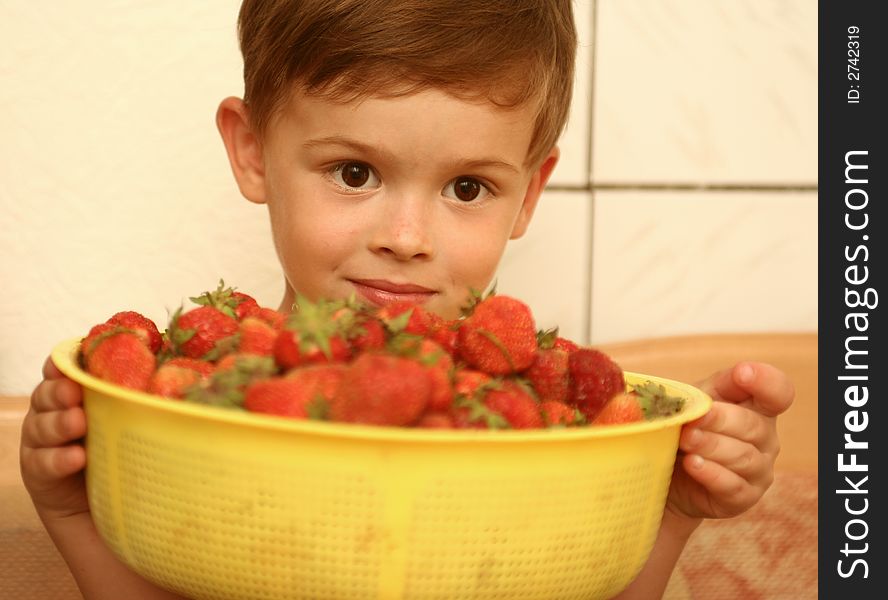 The child looks at a plate with red berries