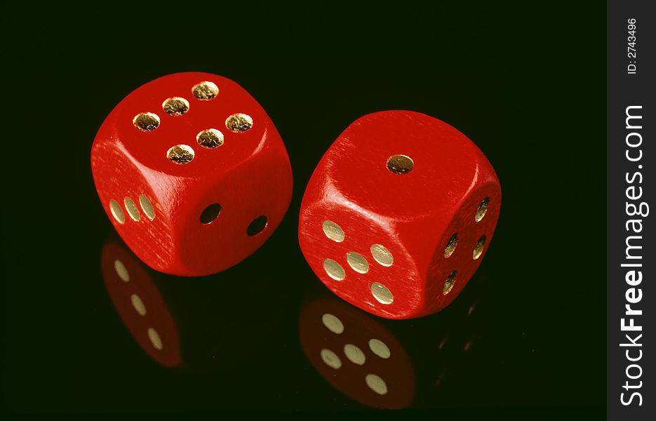 Two red dices on a black surface, showing one and six