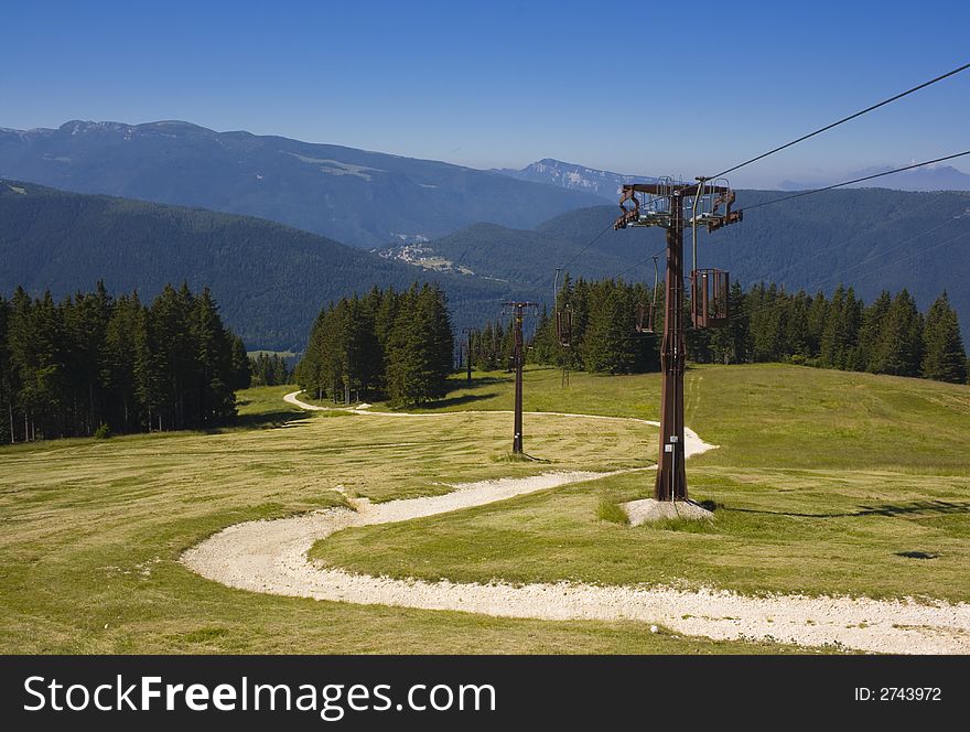 Old cableway in alps with road, forest and mountains in a background