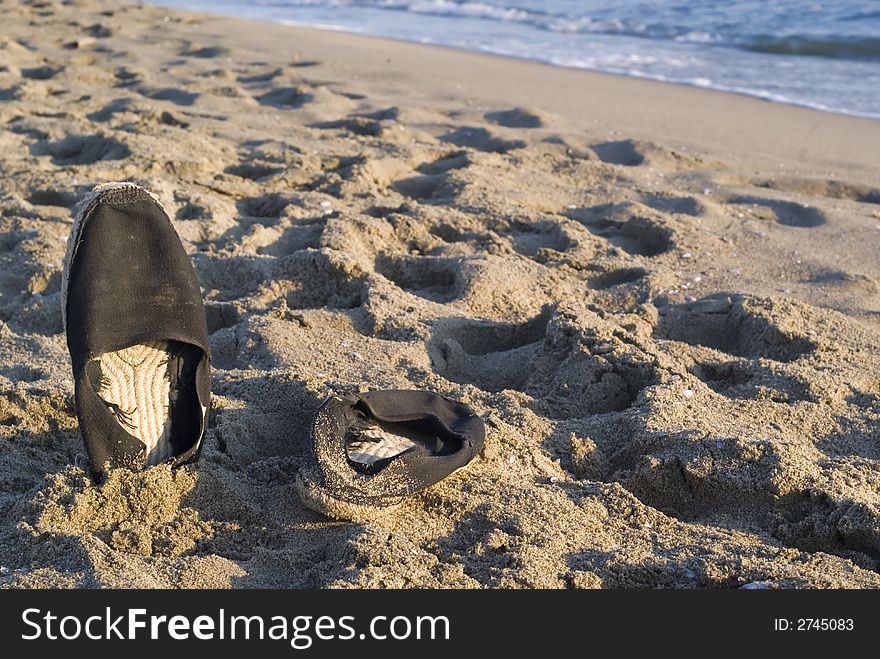 Stylish beach shoes photographed on the sand at sunset. Composition leaves a lot of space for typing. Stylish beach shoes photographed on the sand at sunset. Composition leaves a lot of space for typing