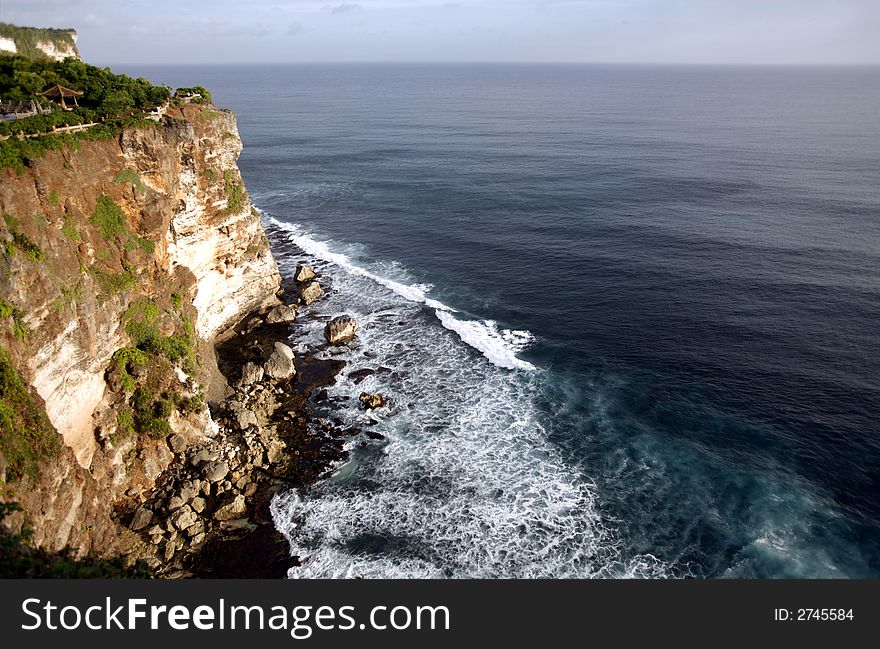 A steep cliff, water and sea.