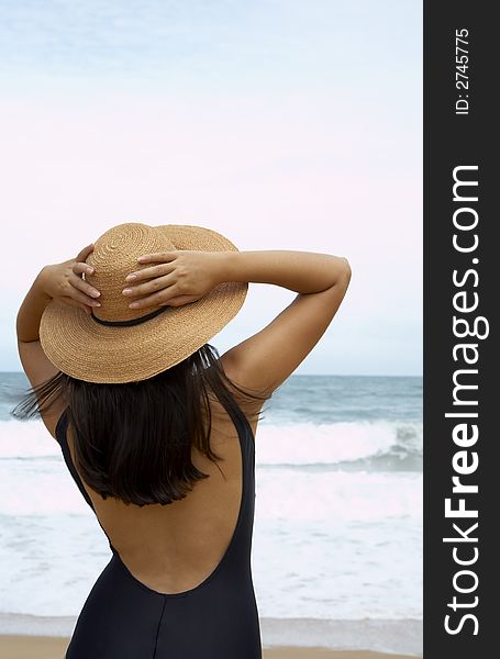 View of nice woman in black swimming wear holding her straw hat. View of nice woman in black swimming wear holding her straw hat