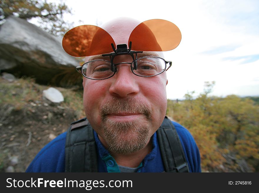 Wide angle egg head hiker upclose with flip shades for his glasses. Wide angle egg head hiker upclose with flip shades for his glasses