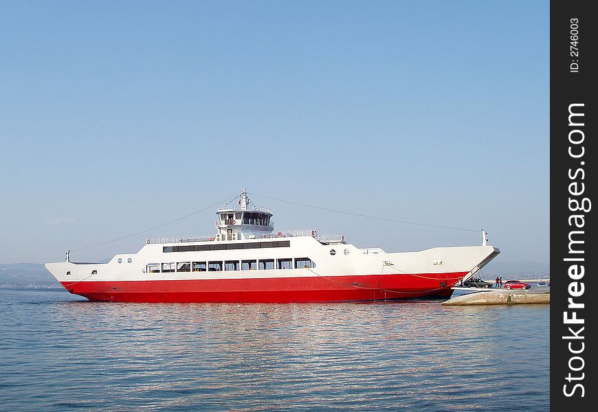 Red ferry boat docked unloading passengers and cars