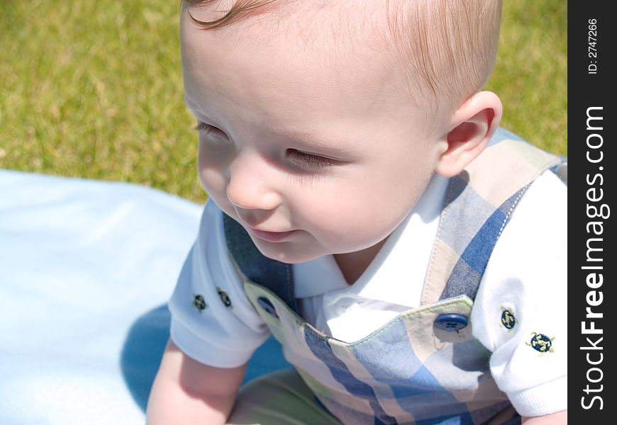 A very cute little infant sitting outside. A very cute little infant sitting outside