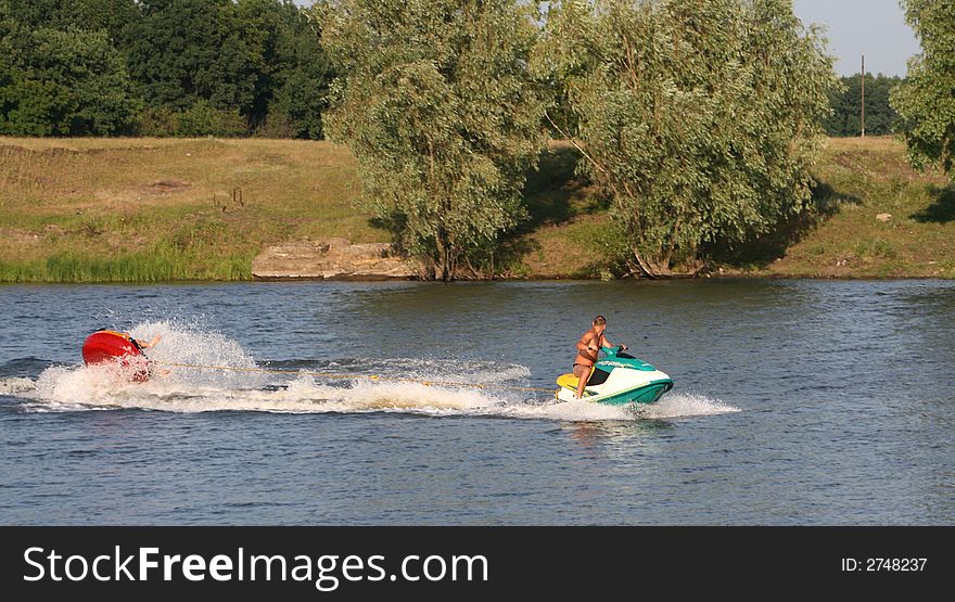 Years summer entertainments on the river. Towage of a rubber boat