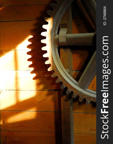 An old wooden flour mill gear on a wall with sun shadows. An old wooden flour mill gear on a wall with sun shadows