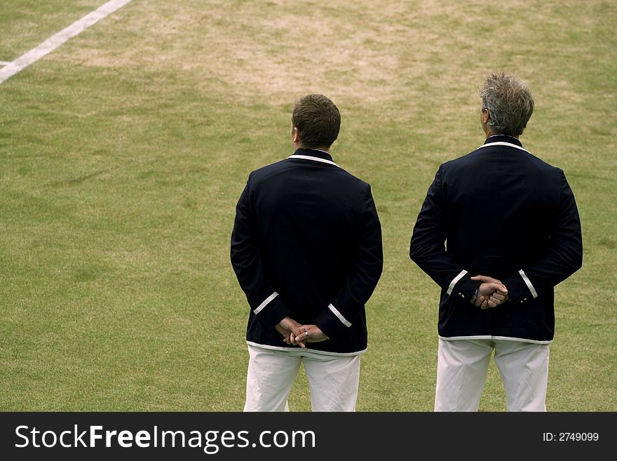 2 Tennis officials observe the going ons of a professional tennis match with baseline in view. Plenty of copyspace.