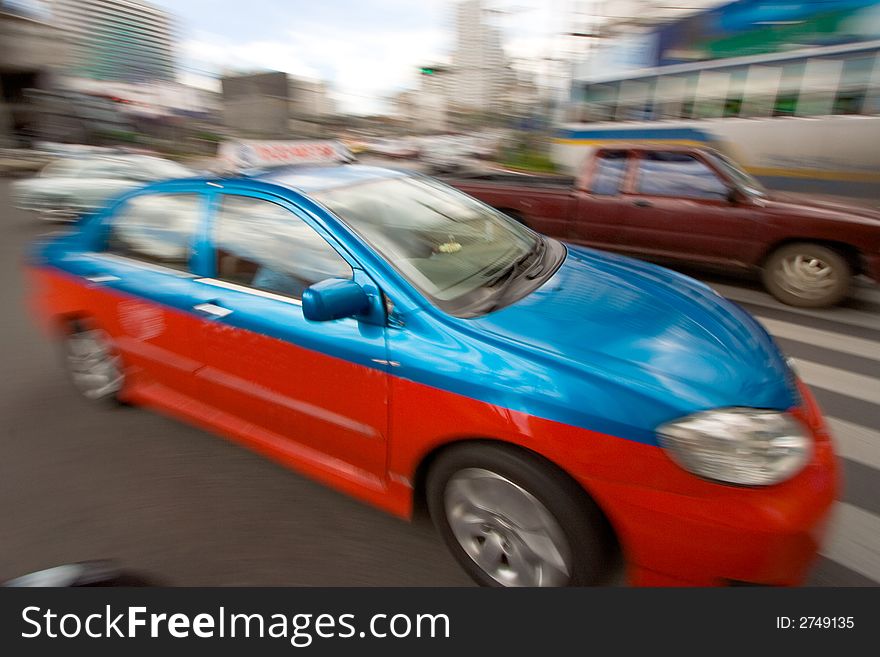 Speeding taxi in downtown traffic driving by on a city street. Speeding taxi in downtown traffic driving by on a city street