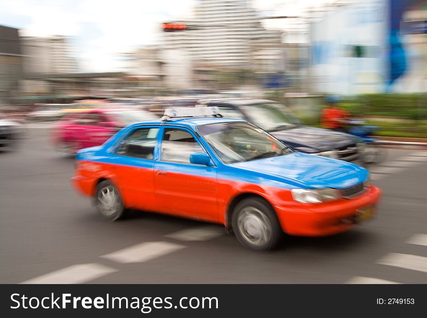 Speeding taxi in downtown traffic driving by on a city street. Speeding taxi in downtown traffic driving by on a city street