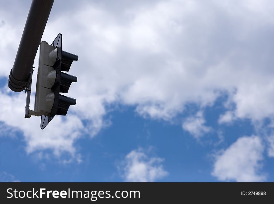 View to above: Stoplight hangs from above into the picture. Background great blue sky with nice clouds. Concept. For beginning or stopping?. View to above: Stoplight hangs from above into the picture. Background great blue sky with nice clouds. Concept. For beginning or stopping?