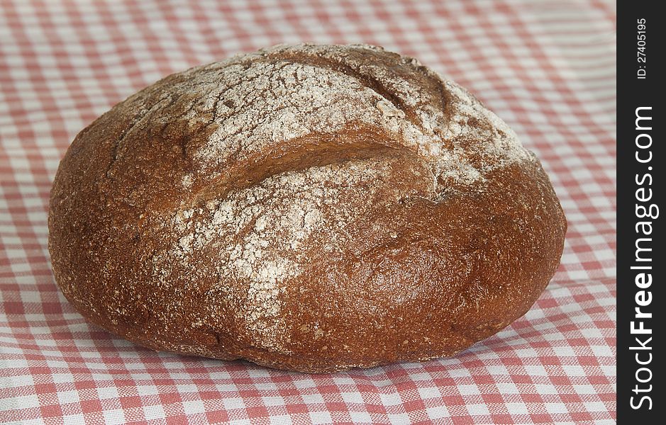 Loaf of round rye bread on a linen napkin in a pink section