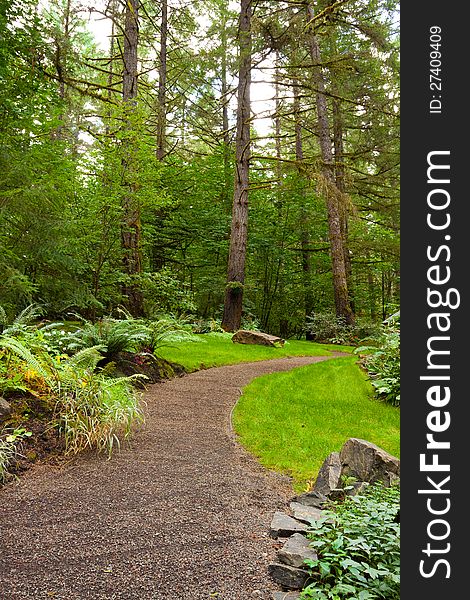 A beautiful path leads into a perfectly manicured garden at an Oregon wedding venue location. There is green, trees, plants, and stone in this vertical image. A beautiful path leads into a perfectly manicured garden at an Oregon wedding venue location. There is green, trees, plants, and stone in this vertical image.