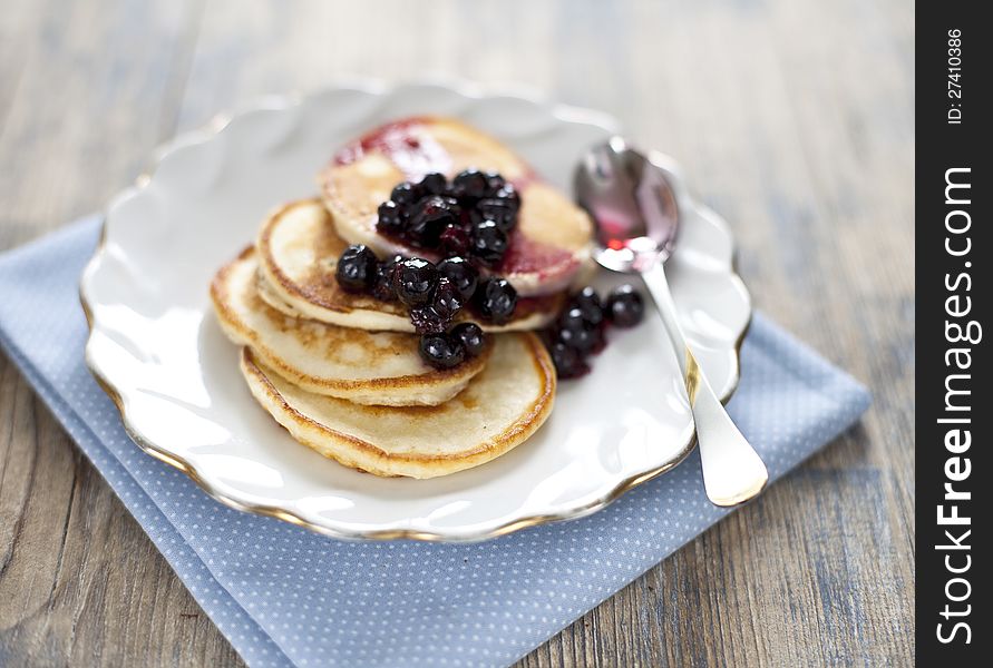 Pancakes with black currant jam on a wooden background