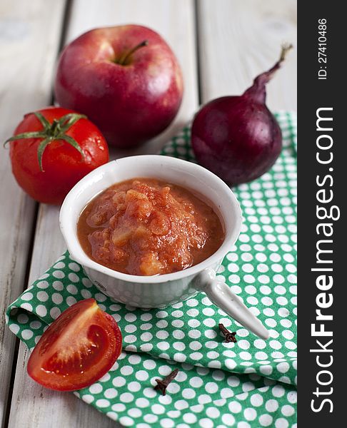 Red spicy sauce with apples and tomatoes in a porcelain scoop