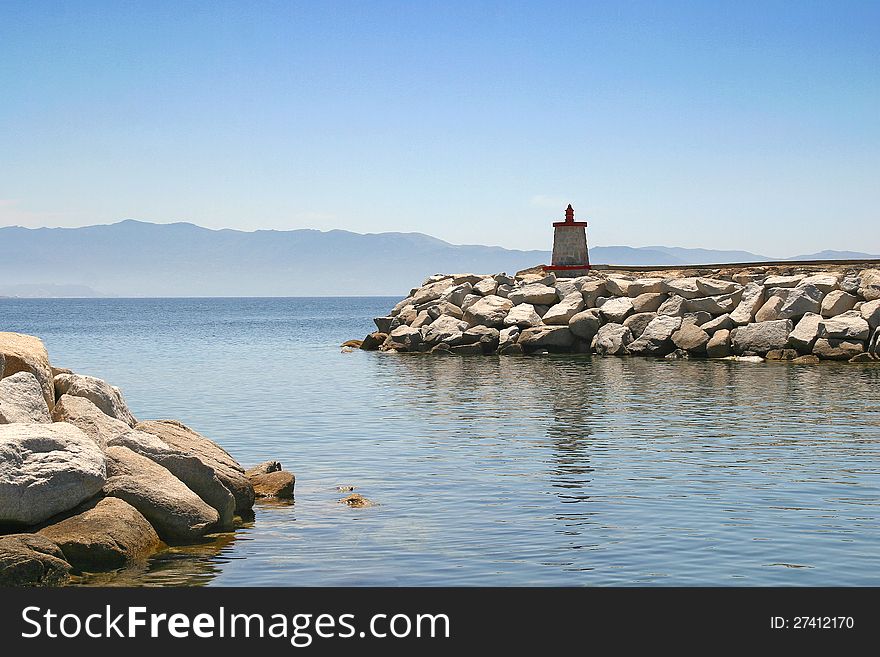 The red stone lighthouse at the harbor entrance