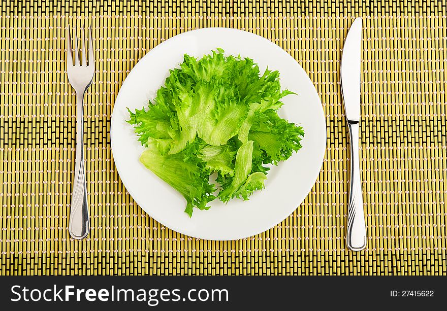 Diet concept. green leaf lettuce on a plate with a fork and knife. Diet concept. green leaf lettuce on a plate with a fork and knife