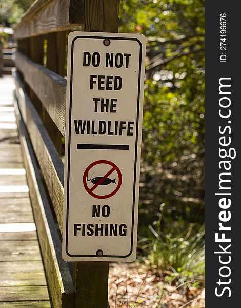 A black and white warning sign that says, & x22 Do Not Feed The Wildlife and No Fishing& x22