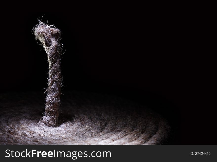 Coil of old hemp rope on black background with free space for text. Coil of old hemp rope on black background with free space for text