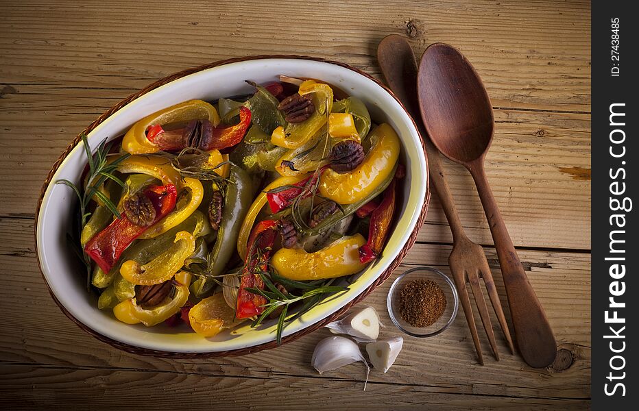 Dish of roasted paprika with pecan and rosemary. A rustic still life.