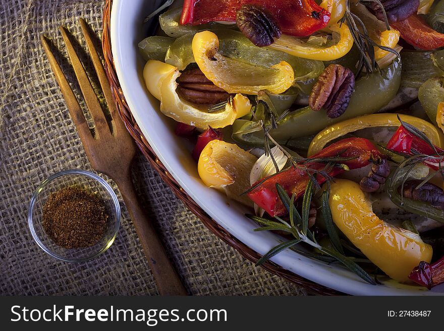 Dish of roasted paprika with pecan and rosemary. A rustic still life.