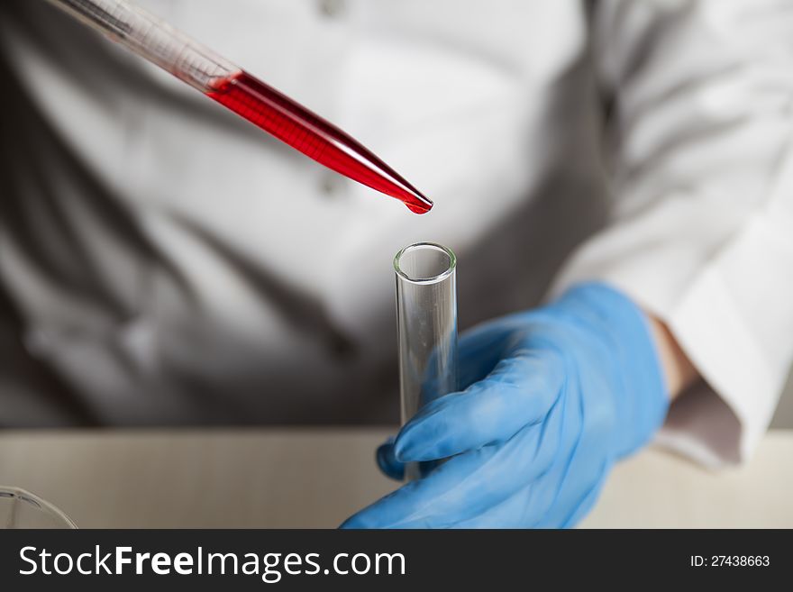 Human hand filling in red liquid from pippette into burette. Human hand filling in red liquid from pippette into burette