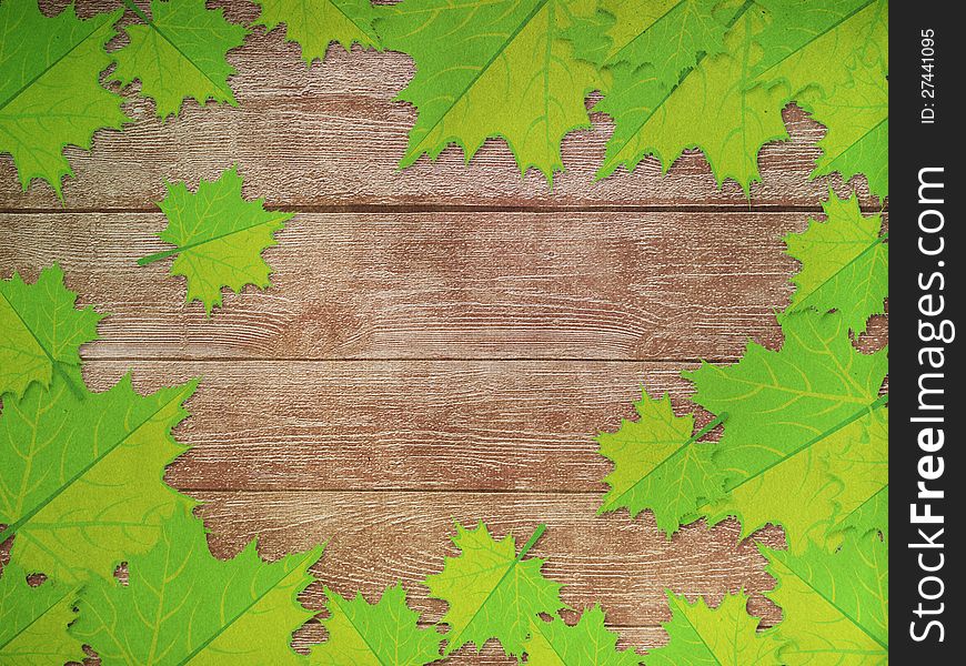 Green maple leaves over wooden background