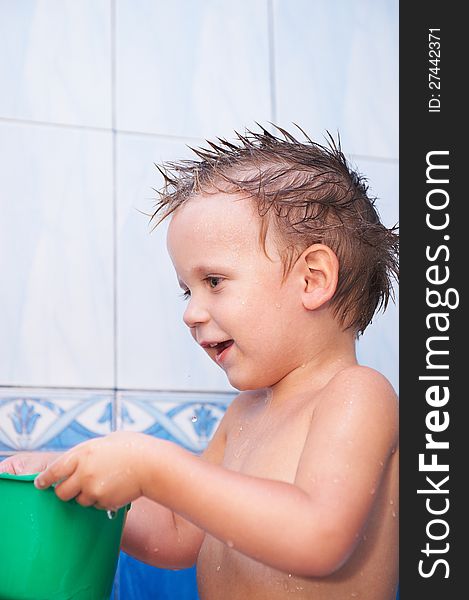 Happy baby in bath with green bucket