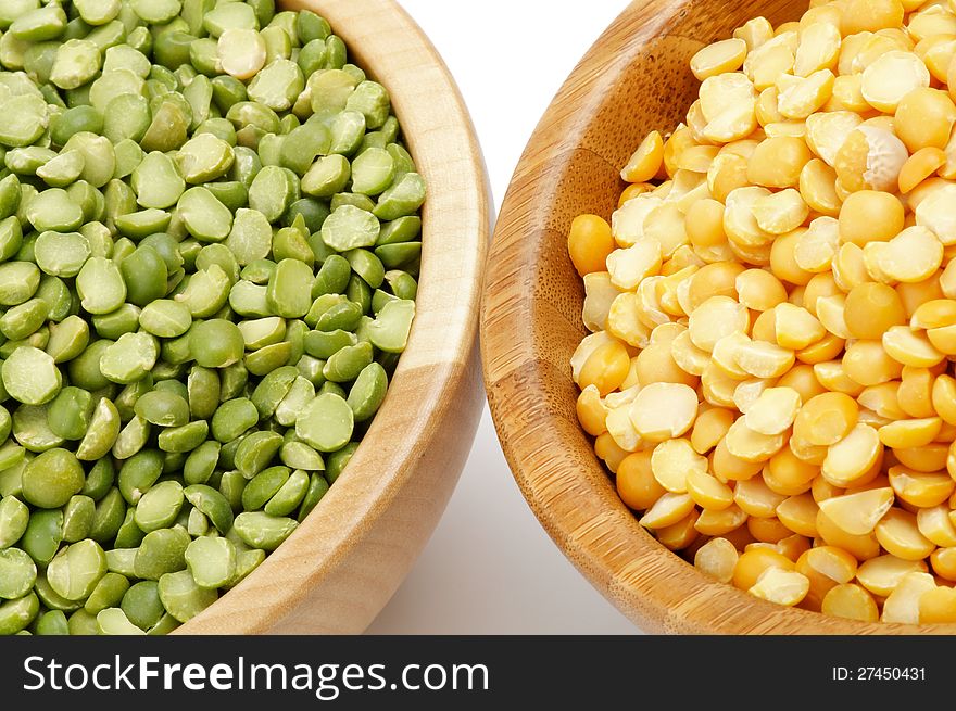 Green and Yellow Split Peas in Wooden Bowls closeup on white background. Green and Yellow Split Peas in Wooden Bowls closeup on white background