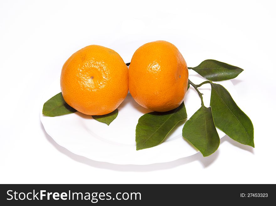 Two tangerines wiht leaves on white plate, isolated on white background
