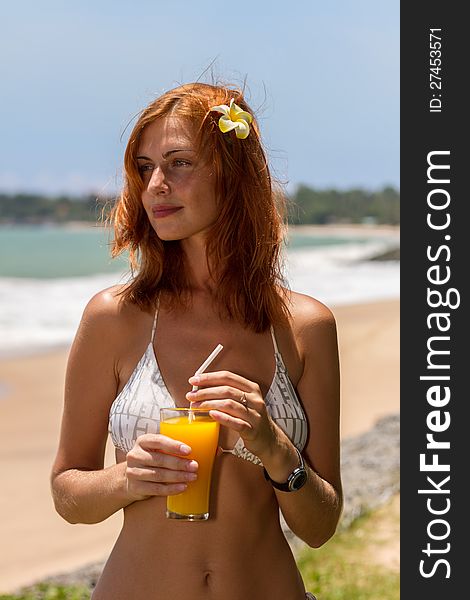 Young woman in bikini with cocktail on the beach