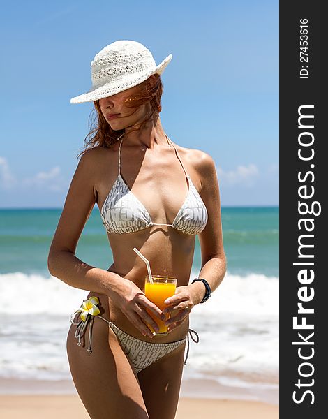 Young woman in bikini with cocktail on the beach