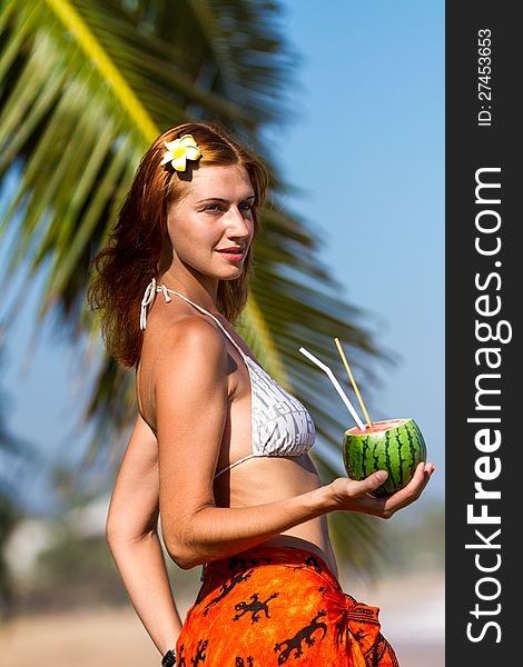 Young woman in bikini with cocktail on the beach