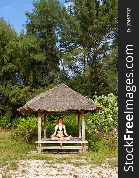 Young woman doing yoga lotus meditation in pavilion near ocean. Young woman doing yoga lotus meditation in pavilion near ocean