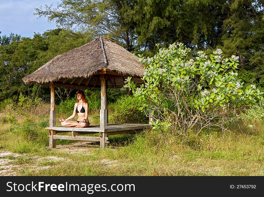 Woman doing yoga meditation in tropical gazebo
