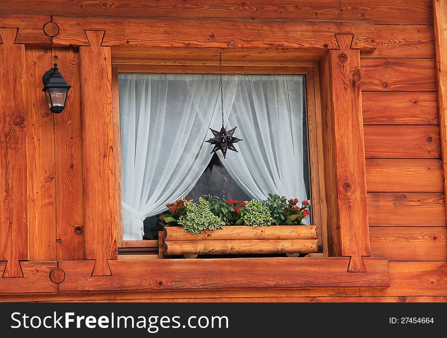 Detail of a mountain chalet wooden window . Flower vase and christmas decoration. Detail of a mountain chalet wooden window . Flower vase and christmas decoration