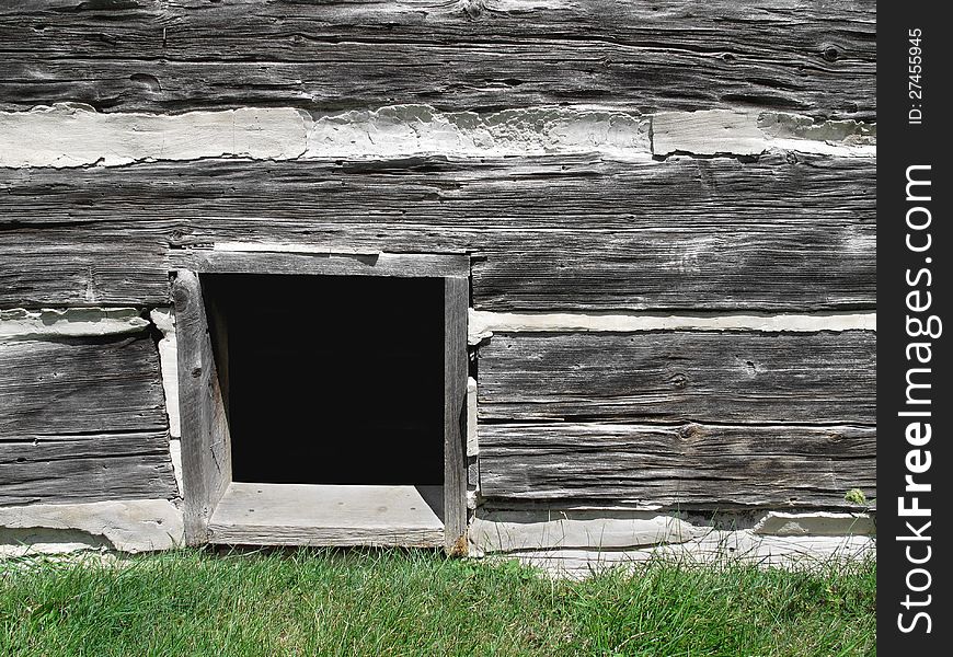 Open basement window on the outside of an old gray log wooden building. Open basement window on the outside of an old gray log wooden building.